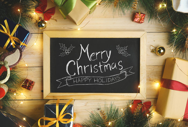 Vue du dessus de la typographie joyeuse de Noël sur le tableau noir entouré par l'ornement de cadeaux de Noël
 - Photo, image