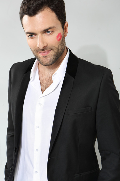 Young caucasian businessman with lipstick kiss mark on his cheek - Fotoğraf, Görsel