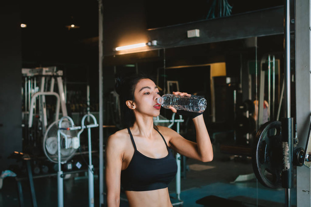 Asian young woman drinking water in the gym. - Valokuva, kuva