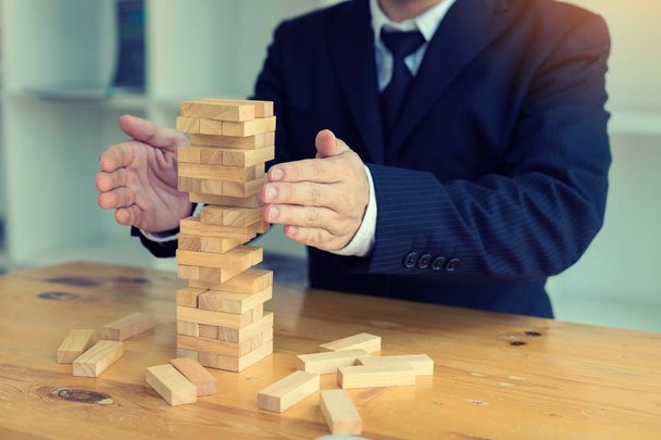 Hands of businessman protect block wooden on table with risk concept. - Foto, imagen
