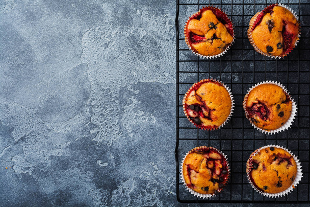 Strawberry chocolate cupcakes muffins on old wooden stand on concrete gray background. Top view. - 写真・画像