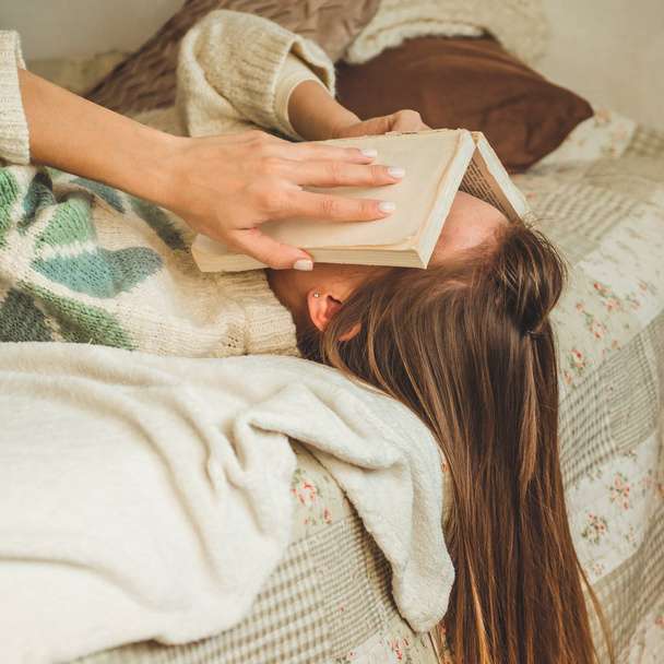 Όμορφη νεαρή γυναίκα ύπνο στο κρεβάτι με το βιβλίο καλύπτει το πρόσωπό της, διότι διαβάζοντας το βιβλίο με την προετοιμασία των εξετάσεων του Κολλεγίου - Φωτογραφία, εικόνα