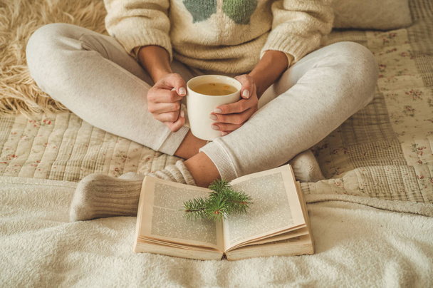 Przytulny dom. Piękna dziewczyna jest czytanie książki na łóżku. Dzień dobry z herbatą. Dość młoda dziewczyna na relaks. Koncepcja czytania - Zdjęcie, obraz