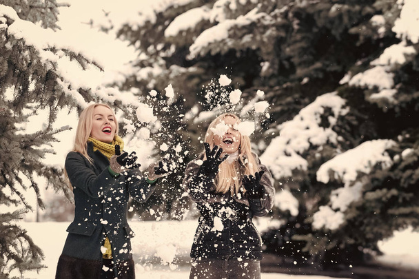 Women or girls playing snowballs in forest on winter day - Foto, afbeelding