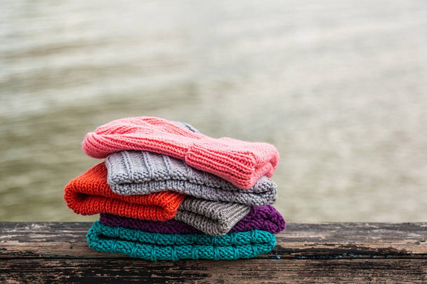 Fundo bonito tricô inverno azul e rosa, vermelho muito chapéu. Crochê gancho artesanal. Close-up de chapéus de malha de azul, amarelo, rosa e cinza
 - Foto, Imagem