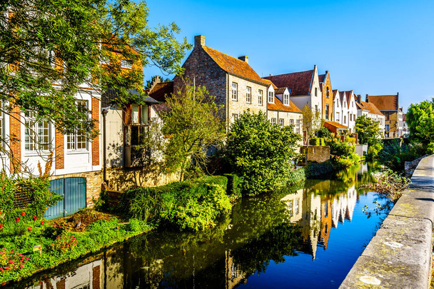 Reflecties van middeleeuwse huizen huizen in het water van een gracht in Brugge, België - Foto, afbeelding