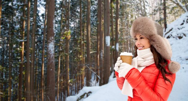 woman in fur hat with coffee over winter forest - Foto, immagini