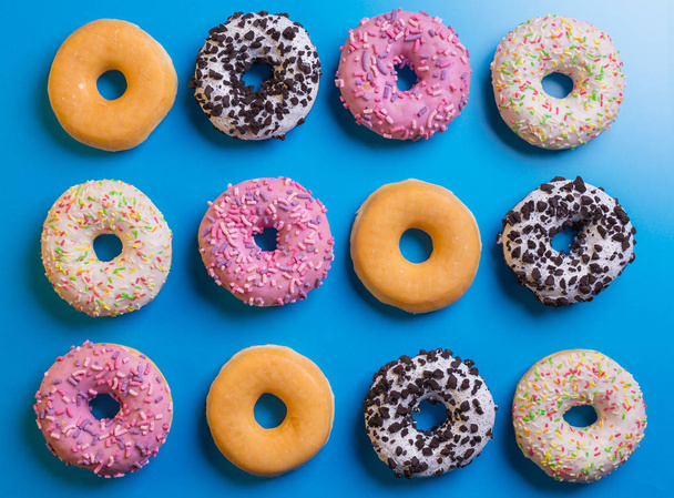 Draufsicht auf viele bunte Donuts auf blauem Hintergrund. - Foto, Bild