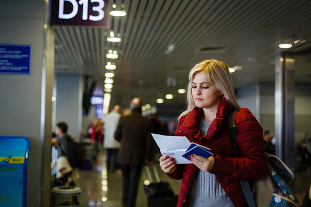 młoda kobieta stojąca przy bramie D13 na lotnisku z dokumentami i biletami - Zdjęcie, obraz