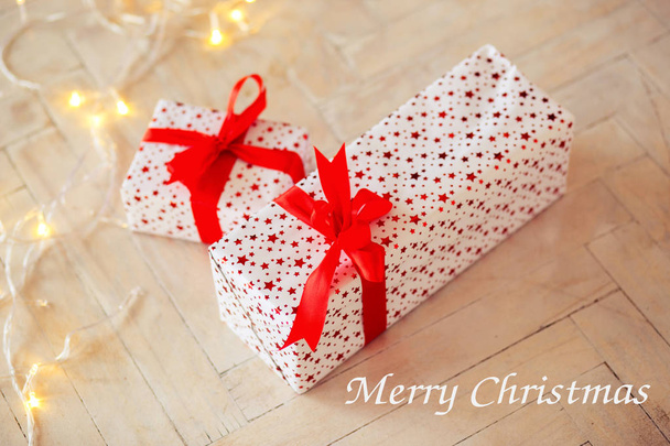 Дві коробки в коробці подарунка лежать на підлозі, зв'язали за червоною стрічкою. Напис на з Різдвом Христовим - Фото, зображення