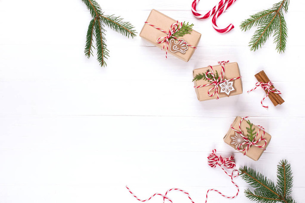 梱包のクリスマス プレゼント。エコ クラフトの休日ギフト ボックスは赤と白の文字列、装飾品、白いテーブルの上の松の枝と関連付けられています。現在はナチュラル パーツで飾られたコピー スペース平面図 - 写真・画像
