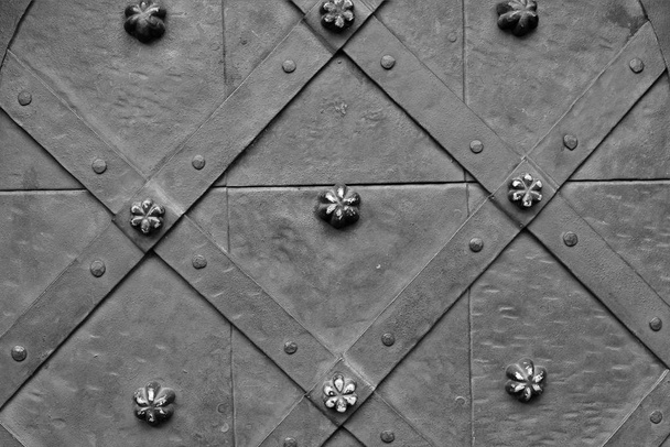 Фрагмент входной металлической двери древнего здания с коваными железными элементами над головой
. - Фото, изображение