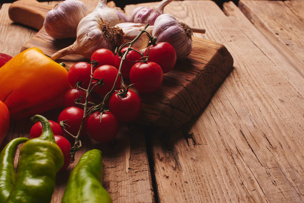 木の板に新鮮な有機野菜をクローズ アップ。チェリー トマト、ニンニク、ピーマン、木製のテーブルのディル - 写真・画像