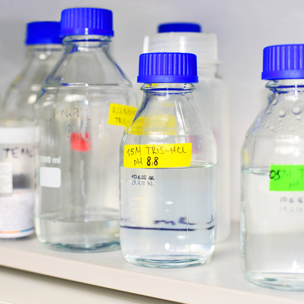 Bottles of buffer solutions stored on a laboratory shelf - Photo, image