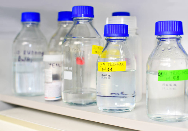 Bottles of buffer solutions stored on a laboratory shelf - Zdjęcie, obraz