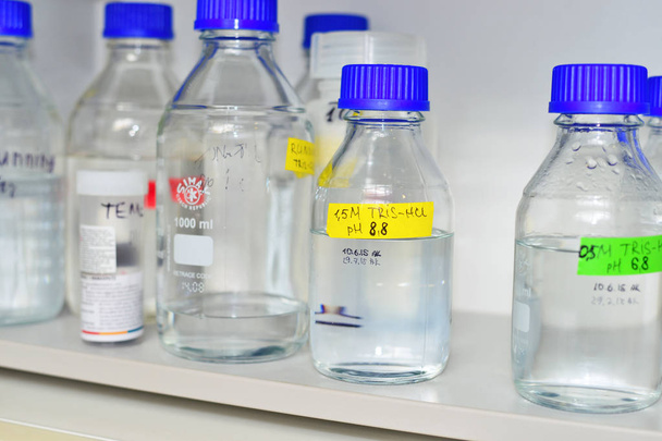 Bottles of buffer solutions stored on a laboratory shelf - Foto, Imagen