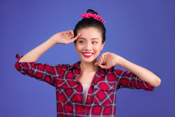 Smiling lovely asian woman dressed in pin-up style dress on lilac background - Photo, Image