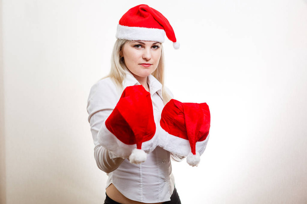 Giovane donna bionda che tiene cappelli di Babbo Natale su sfondo bianco
  - Foto, immagini