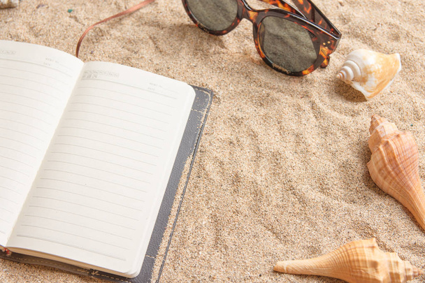 Daily planner on a sandy beach with shells and sunglasses. - Foto, immagini