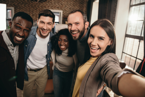 camera point of view of group of cheerful coworkers taking selfie using smartphone  - Photo, Image