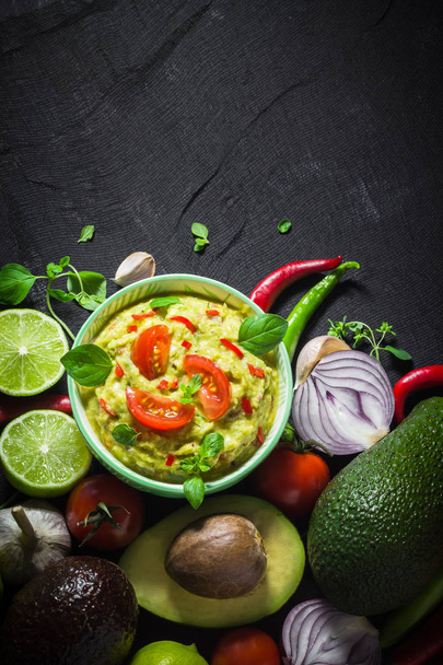 Background with guacamole and ingredients: tomato, chilli pepper, lime, onion, garlic, dill and oregano - Foto, Imagem