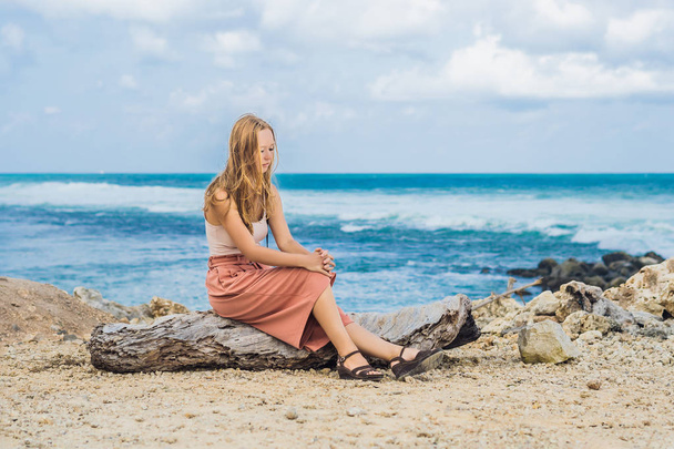 Young female traveler resting on rocks of amazing Melasti Beach with turquoise water, Bali Island, Indonesia. - Photo, image