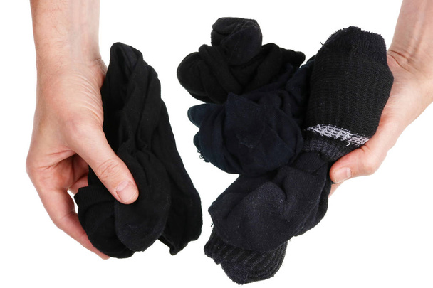 Aus einem Stapel schmutziger schwarzer Socken wählt ein Mann immer das zerrissenste und stinkendste Konzept. isoliert auf weißen Studioaufnahmen - Foto, Bild