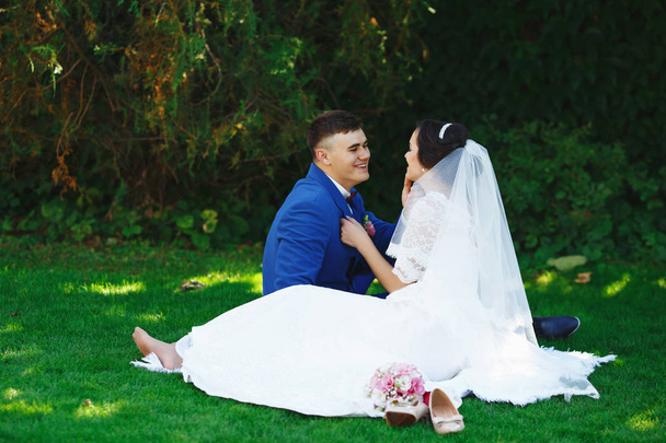 Just married loving hipster couple in wedding dress and suit in the park. Happy bride and groom walking in the beautiful garden. Romantic Married young family. Summer wedding - Photo, Image