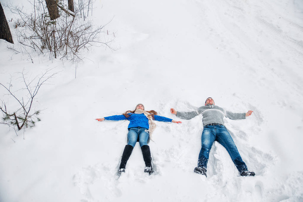 Couple Lying On Snow Making Snow Angel. Winter vacation - Φωτογραφία, εικόνα