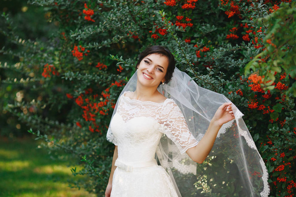 schöne brünette Braut mit Strauß im Freien. glückliche Braut im Freien. schöne Braut posiert in ihrem Hochzeitstag - Foto, Bild