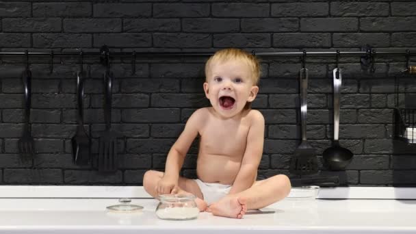 Χαριτωμένο μικρό παιδί είναι χαμογελώντας ζάχαρη tableeating κουζίνα. Άτακτο αγόρι προσπαθεί γλυκά. 4k - Πλάνα, βίντεο