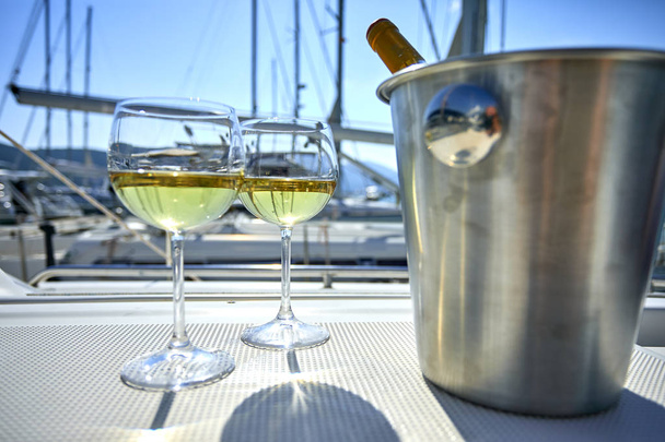 Пара бокалов и ведро с бутылкой белого вина на яхте
 - Фото, изображение