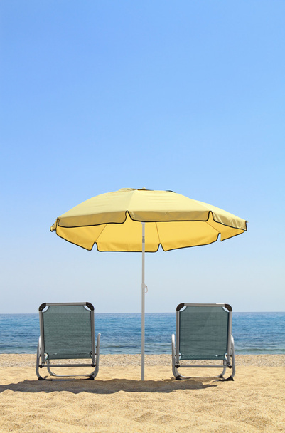 paraplu en lounge stoelen op idyllische strand - Foto, afbeelding
