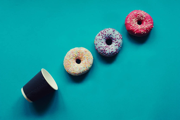 disposable cup and donuts lying on green background - Fotografie, Obrázek