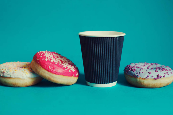  schwarzer Einwegbecher und verstreute Donuts auf grünem Hintergrund - Foto, Bild