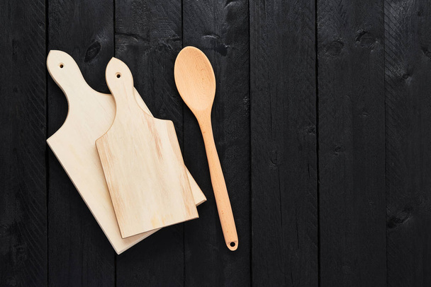 Top view of two chopping boards and spoon on black wooden table with copy space. - Фото, изображение