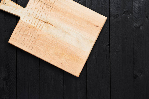Top view of new handmade chopping board on black wooden table with copy space. - 写真・画像