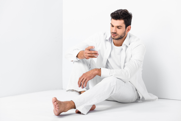 adult handsome man sitting on floor and using smartphone - Photo, image