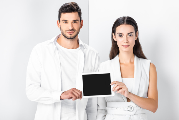 smiling adult couple in total white showing blank screen on digital tablet screen - Photo, image