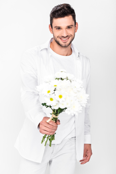 handsome smiling man in total white holding bouquet of white flowers isolated on white - Fotografie, Obrázek