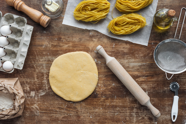 top view of uncooked pasta ingredients and utensils on wooden table - Photo, Image