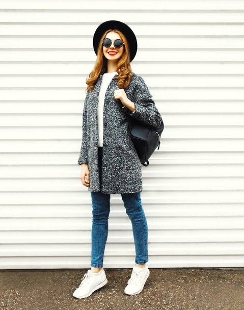 Fashion full-length woman in gray coat, black round hat posing on white wall background on street city - Photo, Image