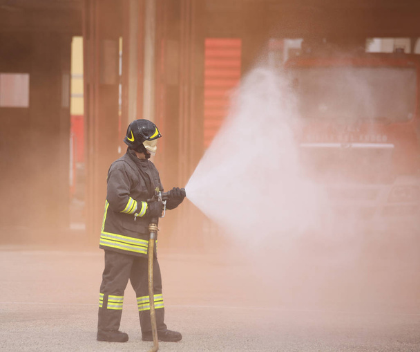 Italia, İtalya - 10 Mayıs 2018: İtalyan itfaiyeci üniforması ve kask ile itfaiyeye yangın musluğu kullanır - Fotoğraf, Görsel