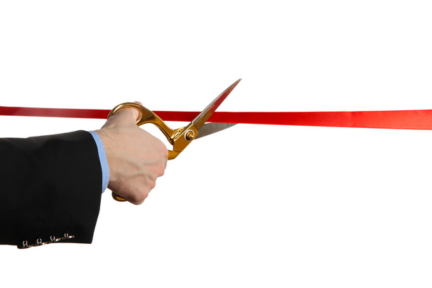 Man's hand cutting red ribbon with pair of scissors isolated on white - Foto, immagini