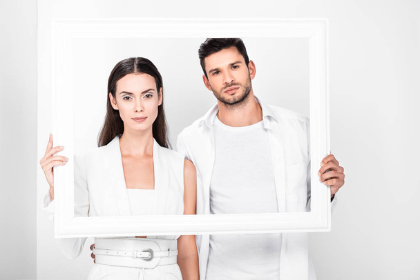 adult couple in total white posing with frame  - Фото, изображение