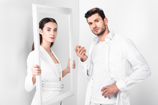 beautiful adult woman holding frame near handsome man on white background  - Zdjęcie, obraz
