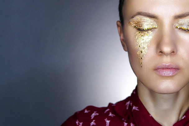 Fashion woman with golden makeup over dark background, half face - 写真・画像