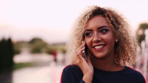 Positivity woman with volumed curly hair talking at call phone and smiling. - Video