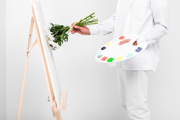 close up of male artist in total white drawing on easel with flowers - Foto, immagini