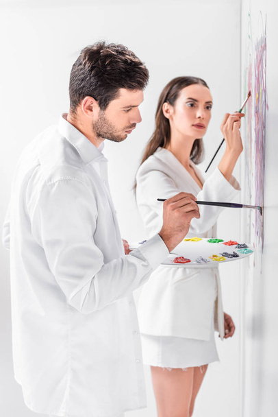 close up of adult couple in total white drawing together on wall - Photo, Image